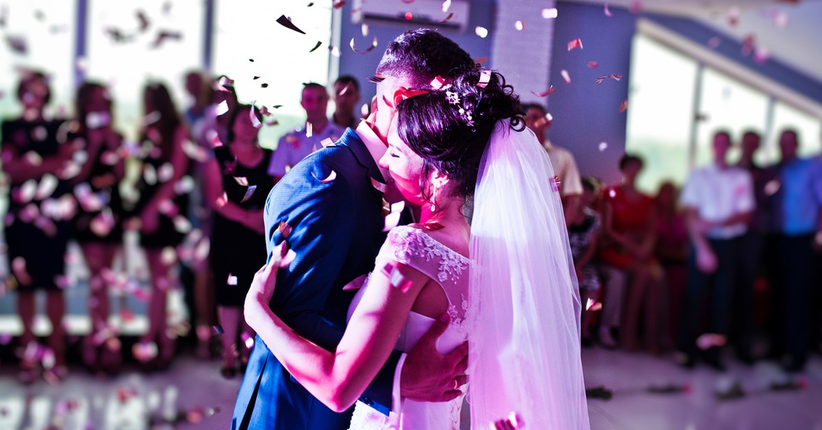 Bride and groom dancing together amidst falling confetti at their wedding.