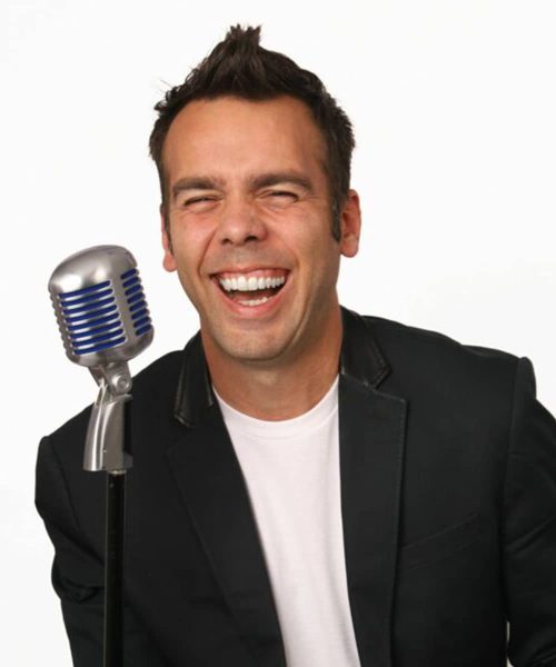 A person laughing while holding a retro microphone against a white background.