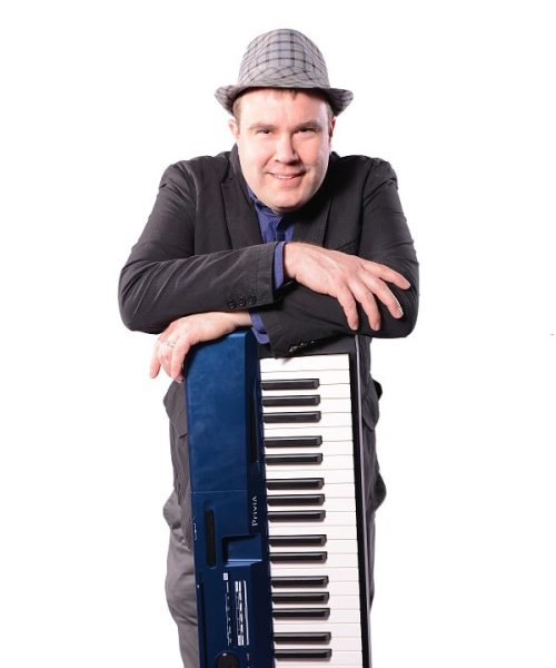 A person in a suit and hat leaning on a keyboard against a white background.